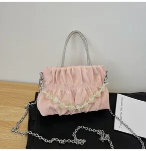 Detailed view of pink pleated handbag featuring rhinestone handles and resin bead chain