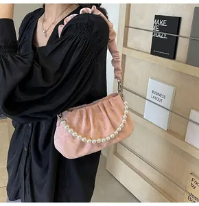 Detail der rosa gefalteten Cloud-Bag mit Perlenkette als stilvolle Unterachseltasche