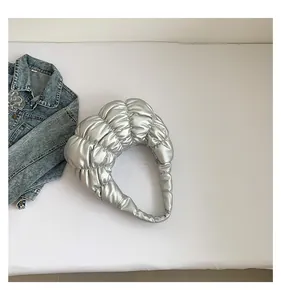 Top view of a silver puffy cloud bag with quilted texture next to a denim jacket