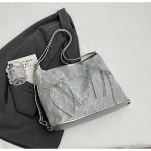 Detailed view of silver tote bag with crinkled metallic texture and bow accents