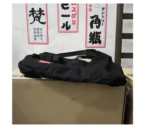 Detail view of durable black nylon crossbody bag with red woven logo on a cardboard box