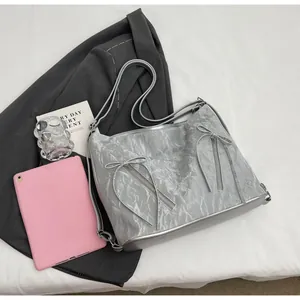 Macro view of metallic silver tote bag with bow-knot zippers and pleated texture
