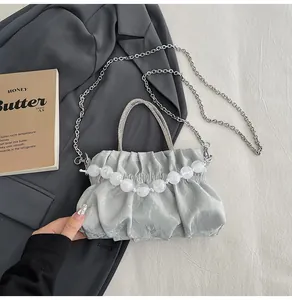 Detail of silver pleated cloud bag featuring glossy satin fabric and pearl bead accents