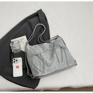 Close-up of silver tote bag with metallic pleated fabric and bow zipper detail