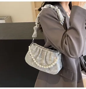 Detail der silbernen Cloud-Bag mit eleganter Perlenkette und stilvollem Griff