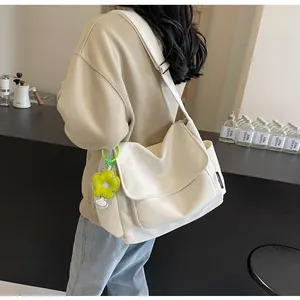 Detail van de gebroken witte canvas crossbodytas met gele zonnebloembedel en geweven zijlabel