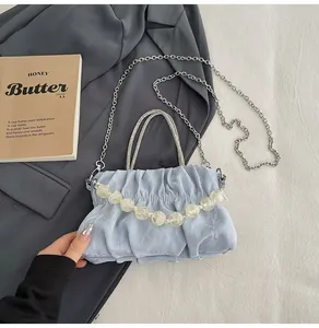 Detail view of light blue pleated handbag with metallic chain and beaded handle