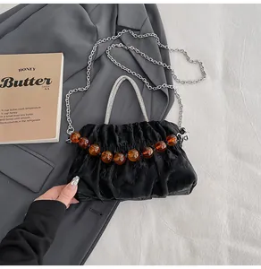 Close-up of black ruched cloud bag featuring diamond-encrusted handle and amber beads