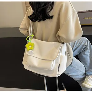 Detailopname van een minimalistische crème canvas crossbodytas met madeliefjesbedel