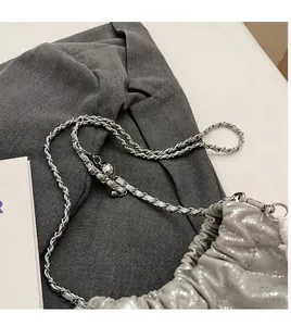 Detailansicht der silbernen Plissee-Tasche mit Kettenriemen und Metallkugel-Verschluss