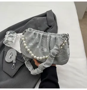Nahaufnahme der grauen Cloud-Bag mit Perlenkette und eleganter Marmor-Textur-Oberfläche