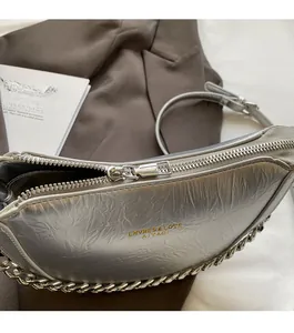 Detailed view of silver metallic pleated dumpling bag with smooth metal zipper closure