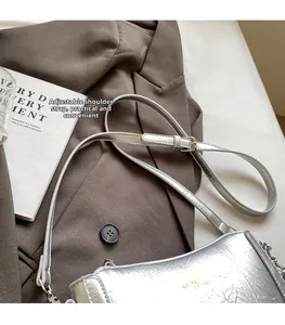 Detail of adjustable leather shoulder strap on silver metallic crossbody bag