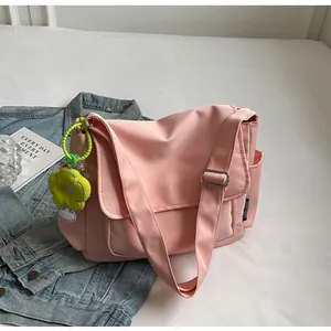 Detailweergave van roze canvas crossbody tas met bloemenhanger en verstelbare riem