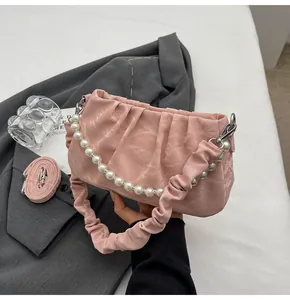 Detail der rosa gerafften Cloud-Tasche mit Perlenkette und Marmortextur-Oberfläche
