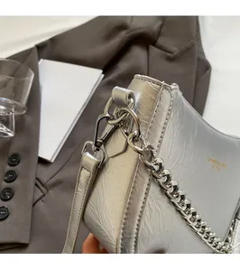 Close-up of silver pleated leather bag with chunky metal chain and golden logo detail