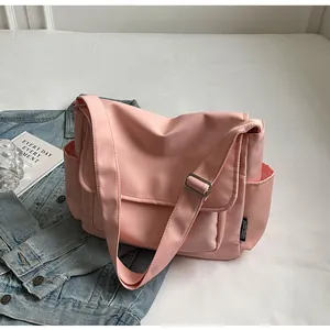 Detail van roze canvas schoudertas met verstelbare riem en zijvak met merklogo