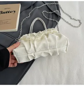 Close-up of pleated cream cloud bag with crystal beads handle and silver chain detail