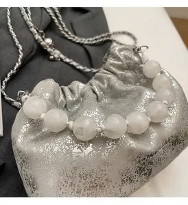 Detailansicht der silbernen Metallic-Beuteltasche mit großem Perlengriff und Kette