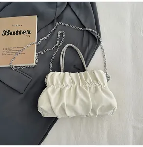 Detail of white pleated cloud bag with silver chain and rhinestone braided handle