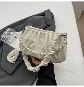 Detailansicht der Cloud Bag mit Perlenkette und cremefarbener gefalteter Riemenstruktur