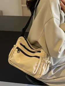 Minimalist beige nylon crossbody bag with black zipper pockets and adjustable strap