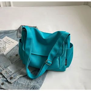 Detail van turquoise nylon crossbodytas met verstelbare brede riem en zijvak
