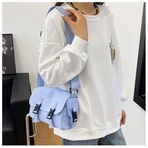 Detail of light blue crossbody messenger bag featuring black plastic buckles and wide strap
