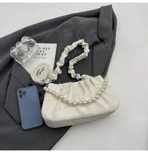 Detail of white pleated cloud bag with pearl chain strap and soft leather texture