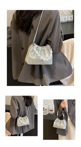 Detail der silbernen Falten-Eimertasche mit Perlen Griff und Metall-Kettenriemen