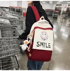 Detail von rot-weißem Laptop-Rucksack mit SMILE-Aufdruck und Entenanhänger im Supermarkt