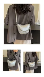 Detail view of silver crescent dumpling bag with metallic texture and chain accent