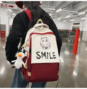 Detail eines Segeltuch-Rucksacks in Rot und Creme mit Graffiti-Lächeln und Entenanhänger