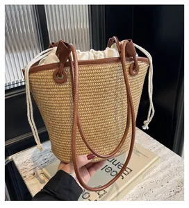Detailed texture of handwoven straw bucket bag with brown leather trim and drawstring insert