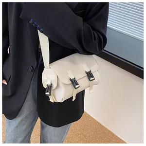 Close-up of minimalist cream crossbody messenger bag with double black buckle closures