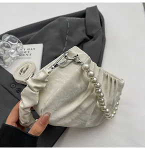 Detail of cream pleated bag featuring marble texture and elegant pearl handle