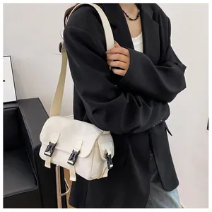 Close-up of a cream canvas messenger bag with black plastic buckle closures on a model