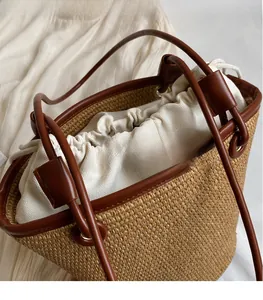 Detail of woven straw bag featuring a leather handle and flower-shaped drawstring closure