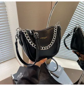 Close-up of black crescent bag with glossy pleated leather and silver chain detail