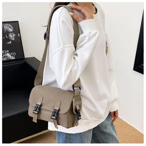 Detailed view of khaki canvas messenger bag with dual plastic buckles and adjustable strap