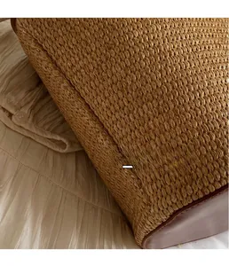 Detail of woven straw bucket bag showing premium stitching and leather bottom panel