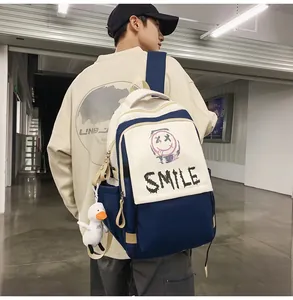 Detail eines blau-weißen Canvas-Rucksacks mit Smile-Print und Plüschenten-Anhänger