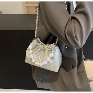 Detail der silbernen Metallic-Faltentasche mit Perlengriff und feiner Ketten-Schulterriemen