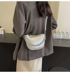 Detailed back view of a silver crescent crossbody bag with chain and pleated texture