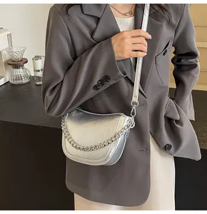 Detail of silver metallic crescent bag with chain strap on model in gray suit