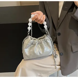Detail der silbernen Cloud-Tasche mit Perlengriff und Metallkette am Modell gezeigt