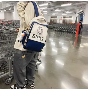 Detail eines navy-beigen Rucksacks mit Smile-Aufdruck und süßem Enten-Plüsch-Anhänger