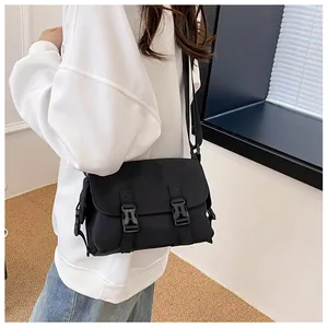 Detail view of a black nylon messenger bag with buckle closures on a female model