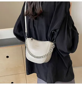 Detail of beige crescent bag with silver chain strap and subtle pleated leather texture