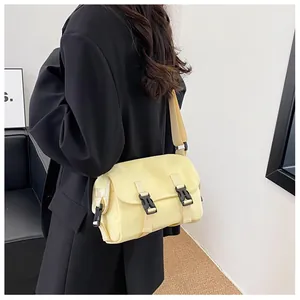 Close-up of yellow messenger bag with black buckles and adjustable strap detail